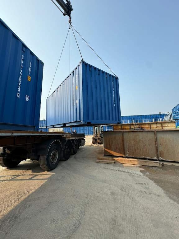 Blue shipping container being delivered using a HIAB lorry
