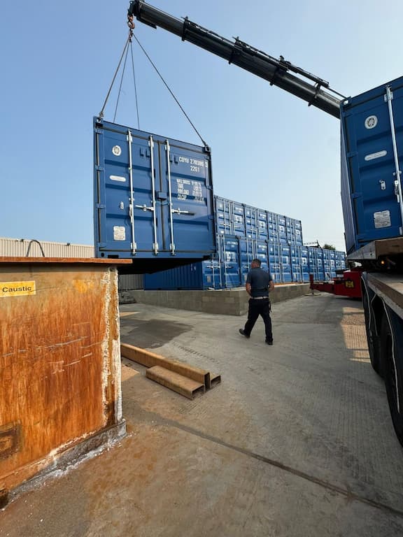 Blue shipping containers being delivered to self storage site